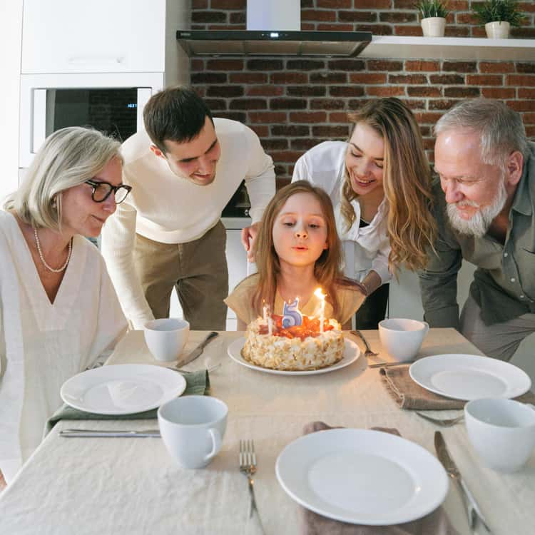 Family around a girl blowing out birthday candles, for Coloring.app's AI photo-to-coloring page tool.